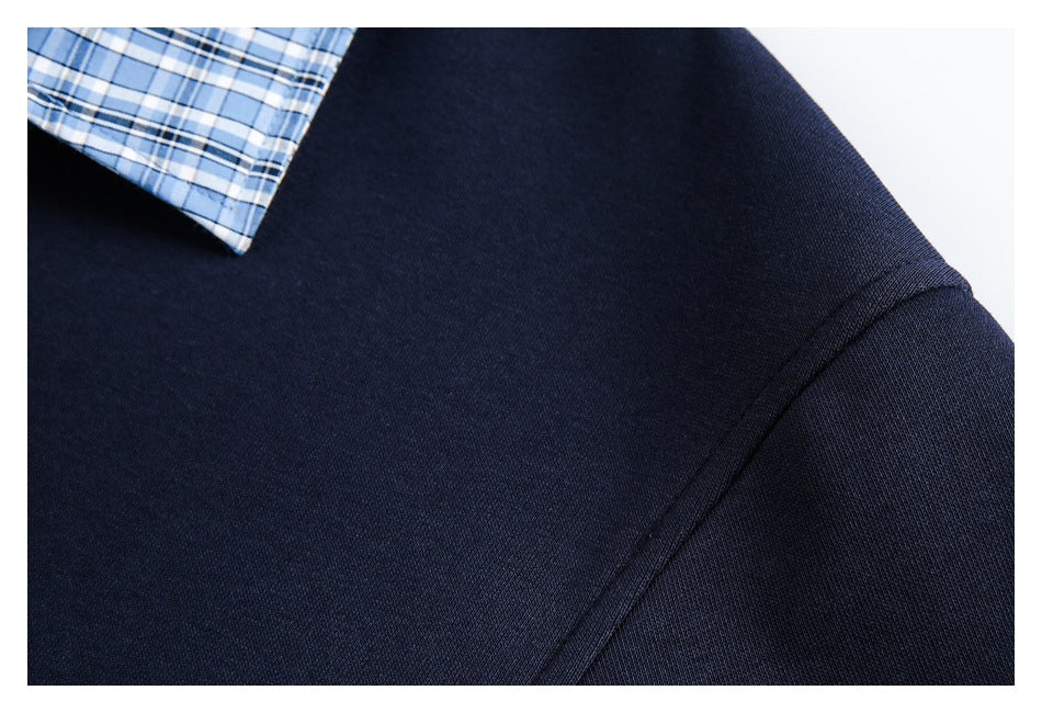 Close-up of a navy polo's shoulder seam and a corner of its blue plaid collar.