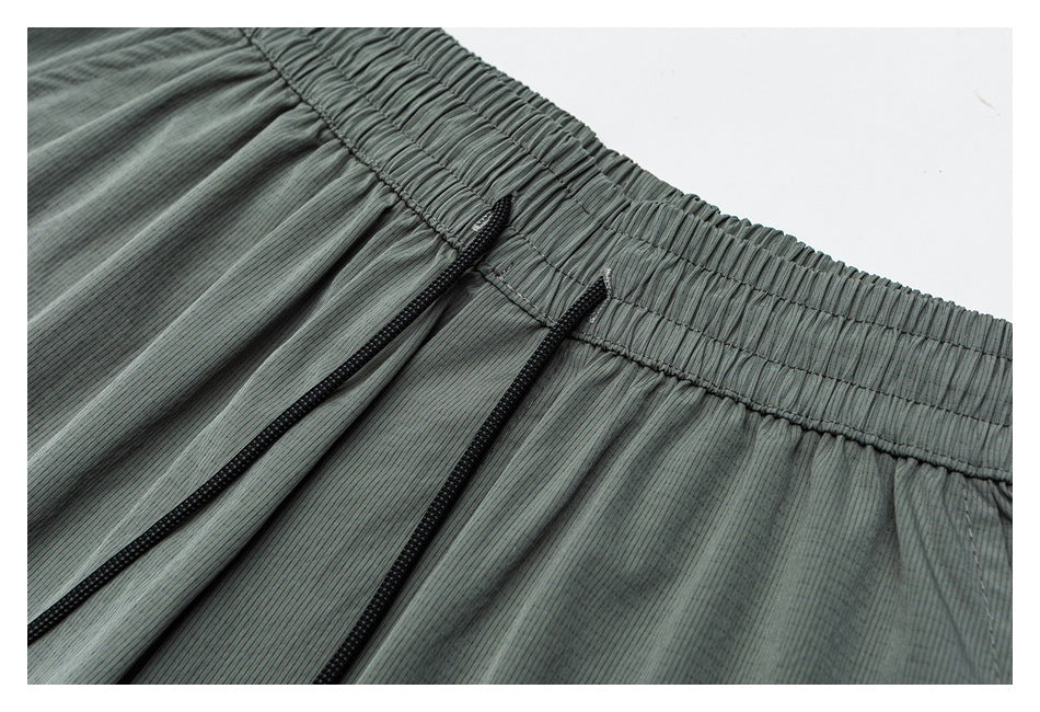 Close-up of a blue-gray striped garment's gathered elastic waistband and two black drawstrings.