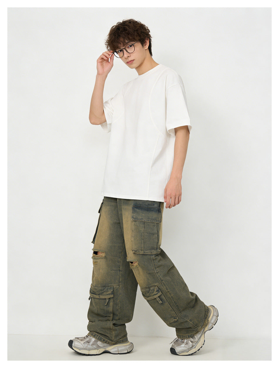 Model wearing a white oversized short-sleeve T-shirt with olive-gray distressed cargo pants.