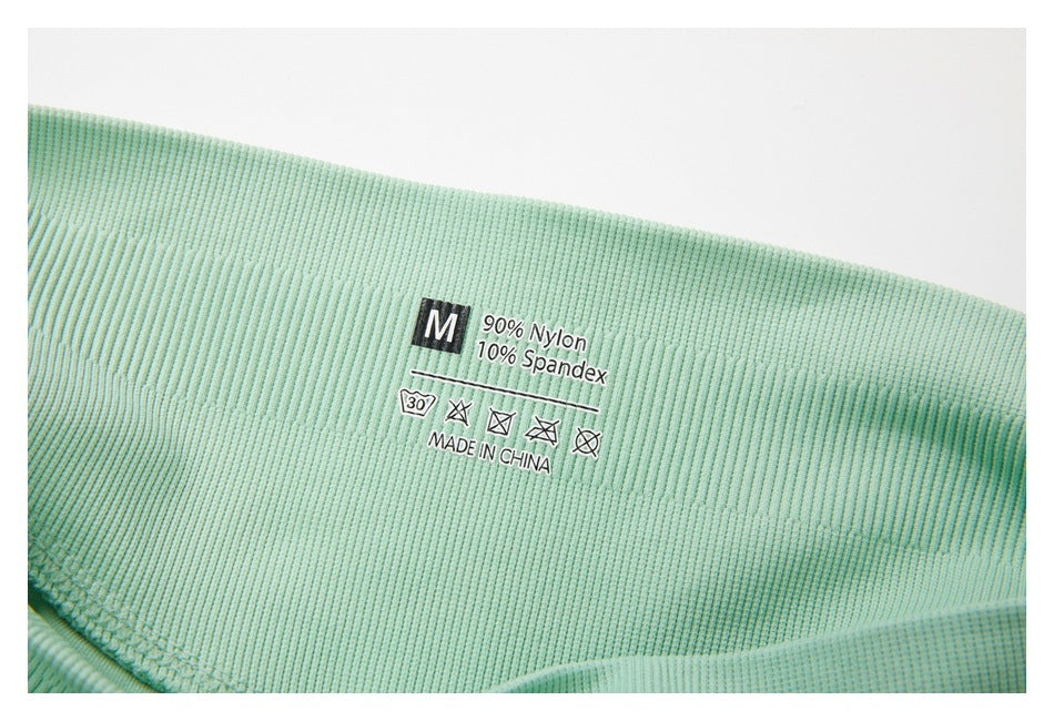 Close-up of a mint-green garment label showing size M, 90% nylon, 10% spandex, and care symbols.