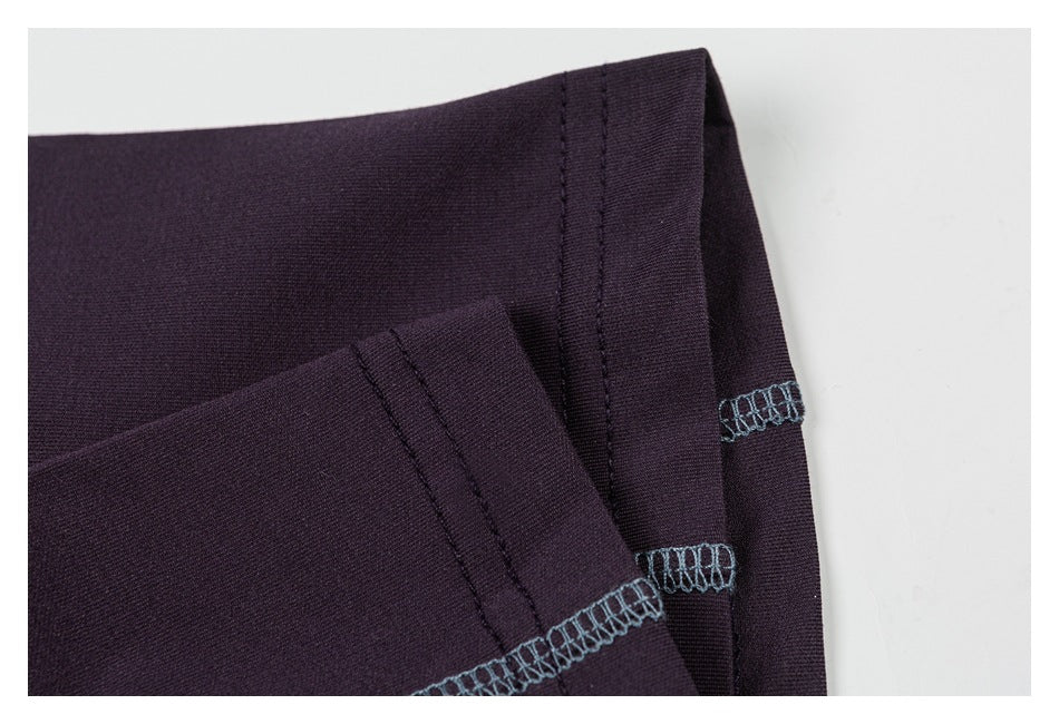 Close-up of folded dark plum garment edges with blue-gray overlock stitching.