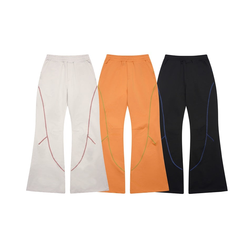 Front view of flared pants in light gray, orange, and black with contrasting curved seam details.