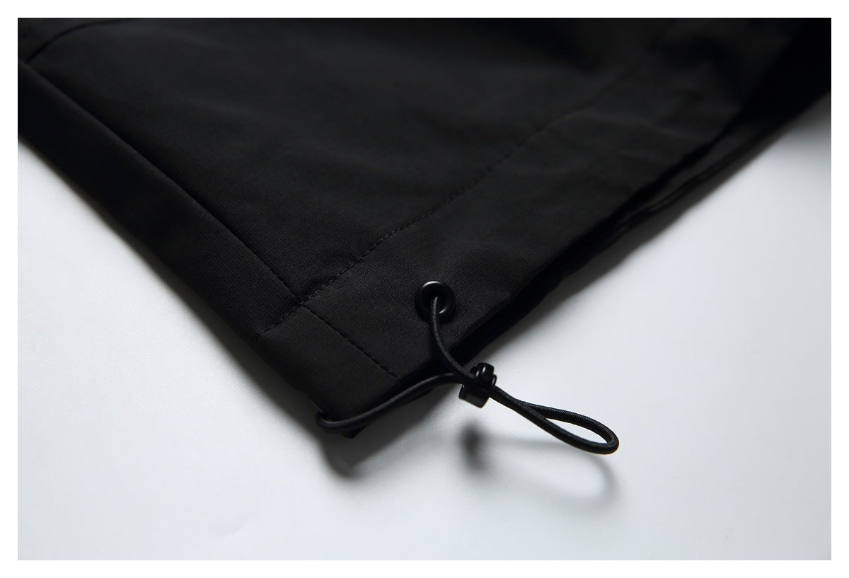 Close-up of a black garment hem with a cord loop and adjustable toggle.