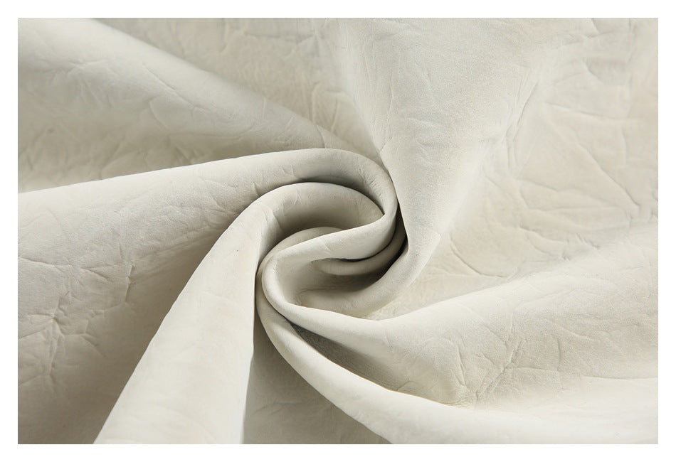 Close-up of ivory fabric gathered into a twist, showing its softly creased surface.