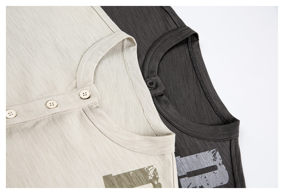 Close-up of cream and charcoal sleeveless shirts with round necks, buttoned plackets, and distressed graphic prints.