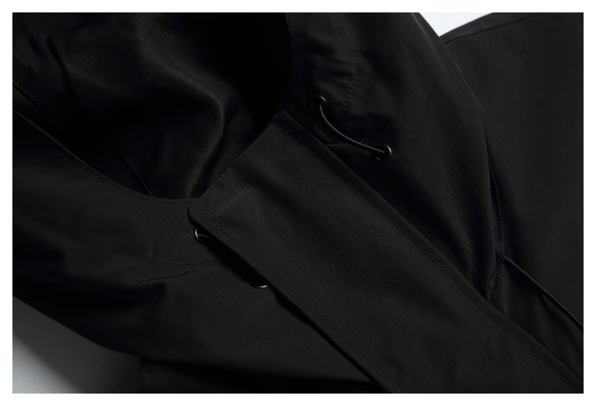 Close-up of a black hood with a drawcord and an overlapping fabric flap.