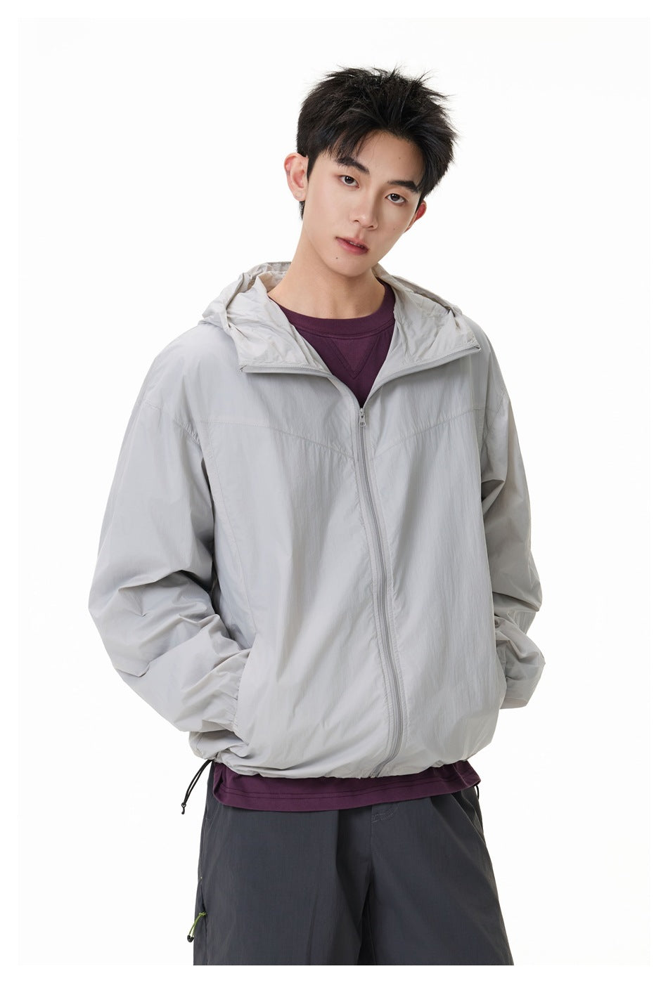 Model wearing a light gray hooded zip jacket over a plum shirt, shown from the front.