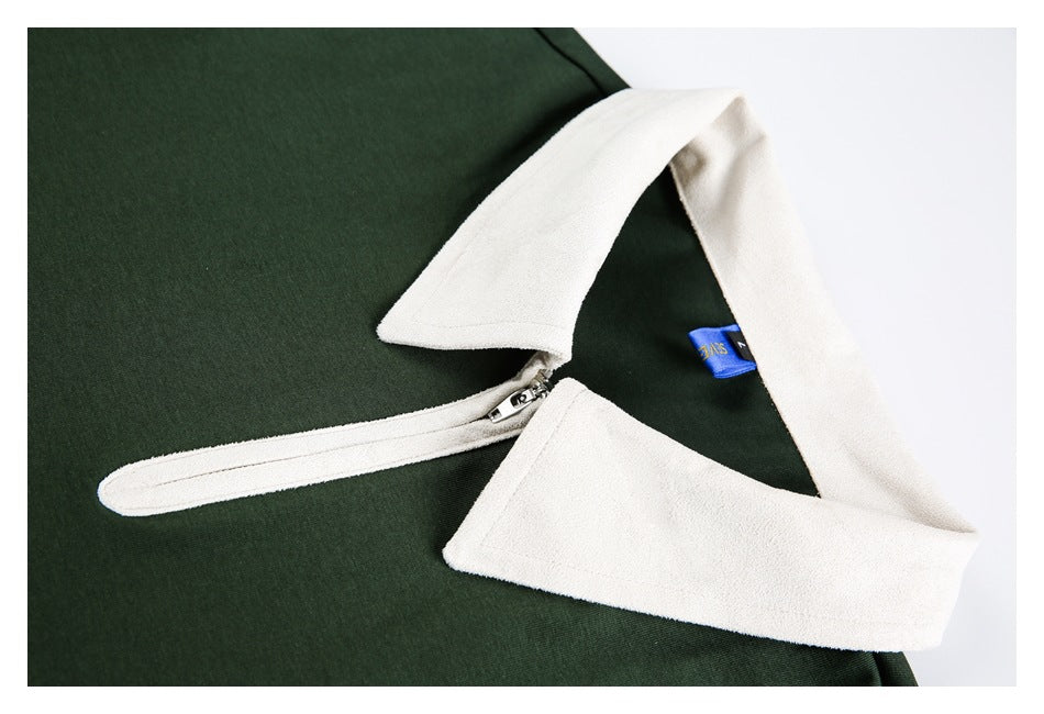 Close view of a dark green top with a wide white collar and short zip placket.