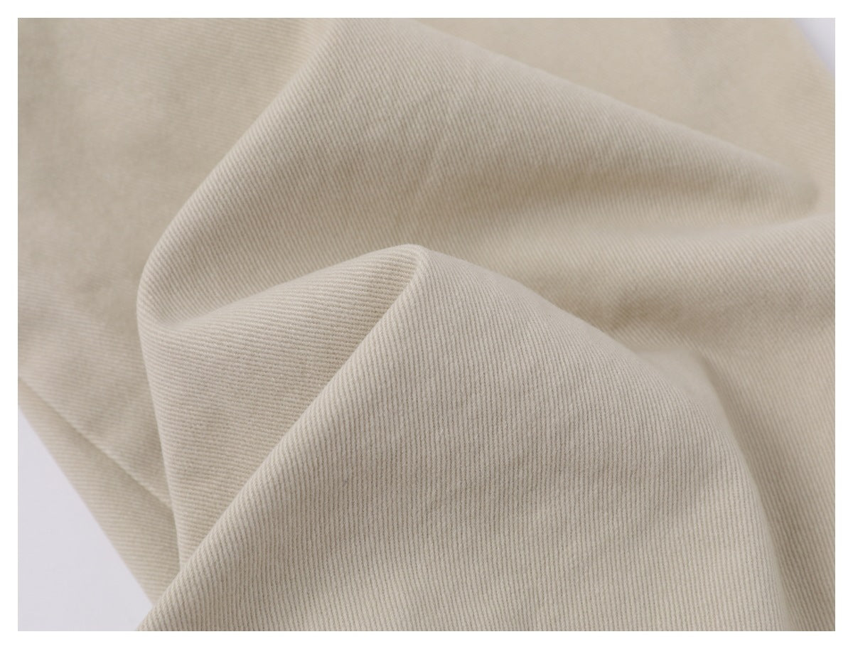 Close-up of the beige trousers' diagonal fabric weave and texture.