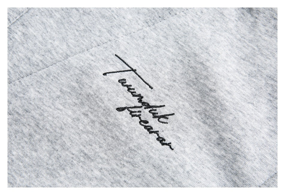 Close-up of black cursive embroidery on heather-gray fabric.