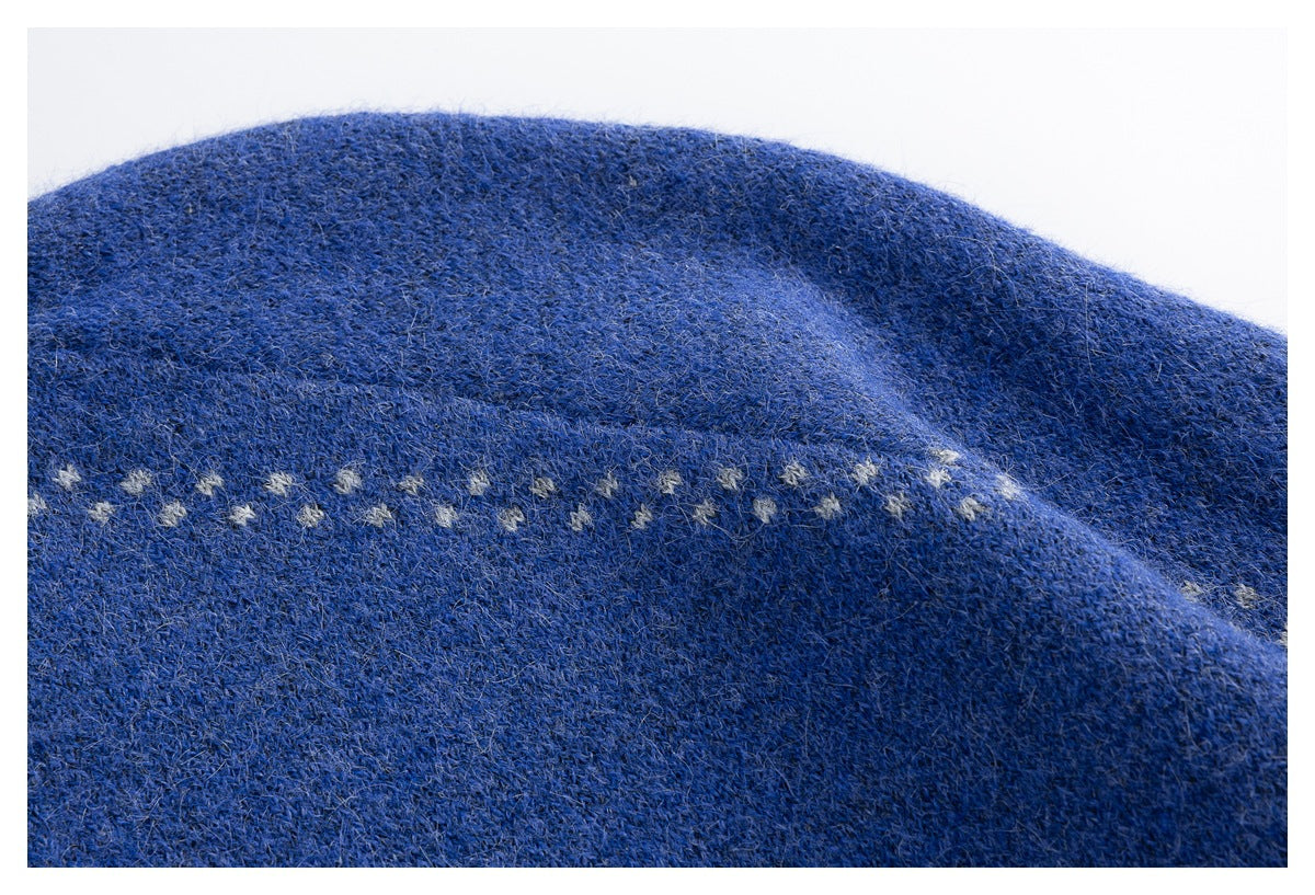 Close-up of blue sweater knit with a horizontal row of small light-colored motifs.