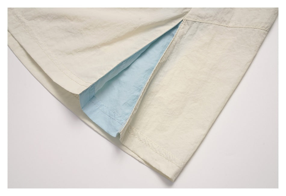 Close-up of a slit in the cream skirt revealing a light-blue inner panel.