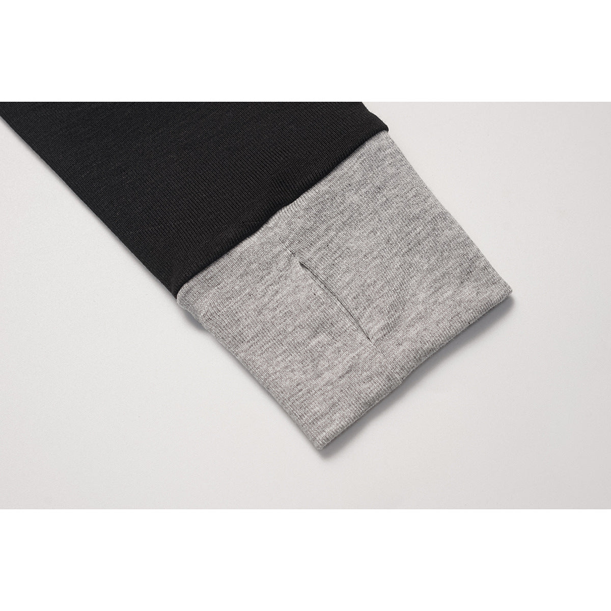 Close-up of a black sleeve ending in a wide heather-gray cuff.