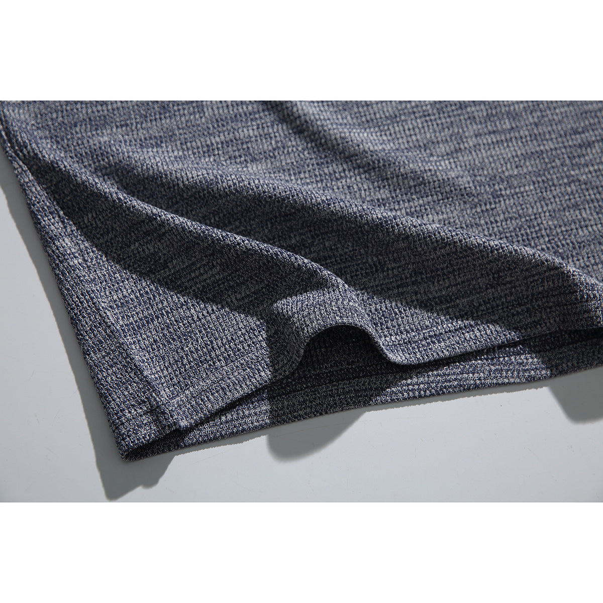 Close-up of the blue-gray shirt's textured fabric and folded hem.