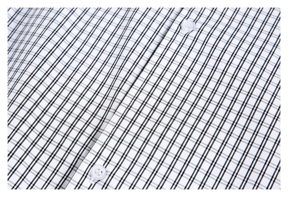 Close-up of two white buttons and a placket on white fabric with a black and gray plaid pattern.