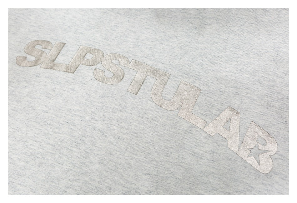 Close-up of large pale lettering printed across the light gray heather T-shirt.