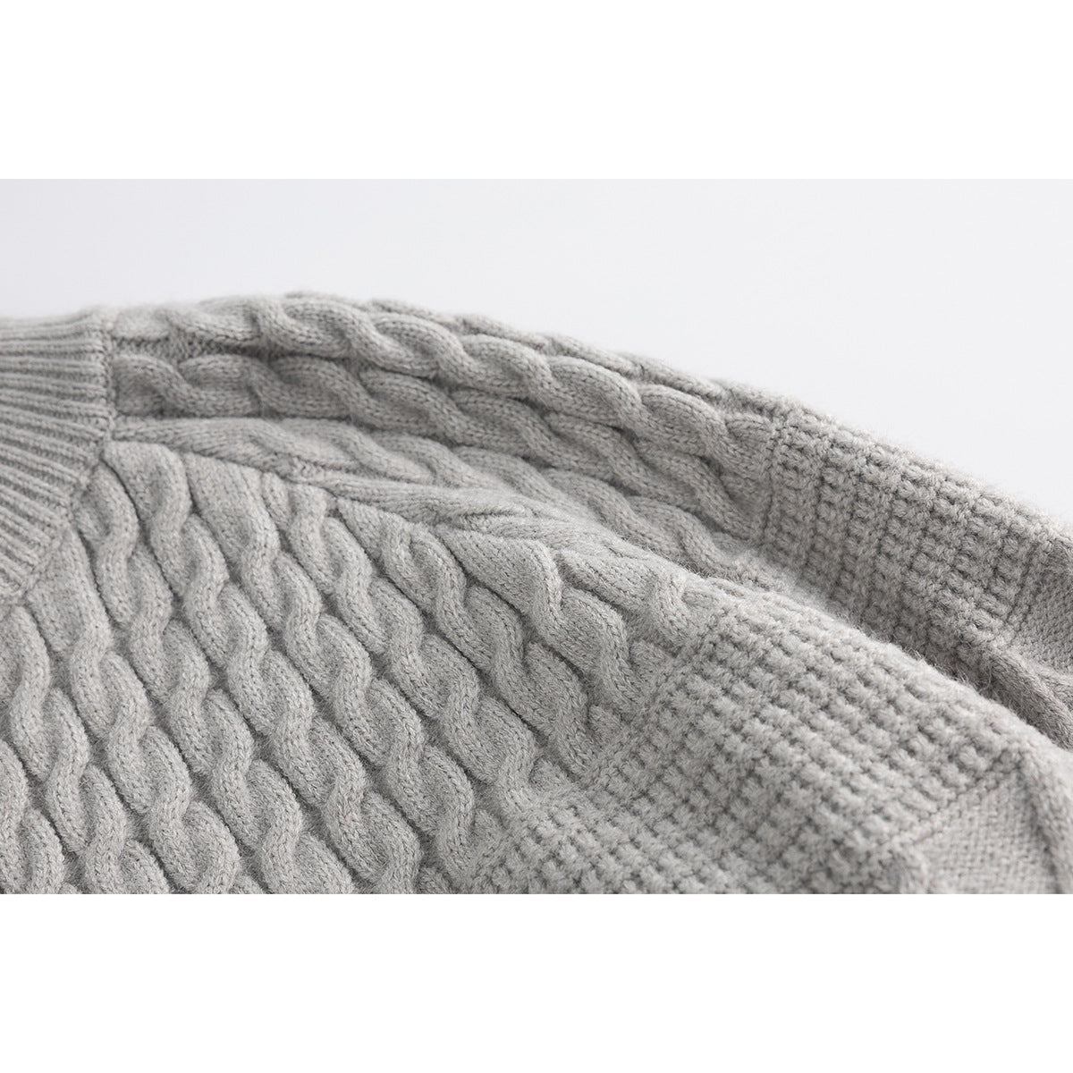 Close-up of the light gray cardigan's cable-knit body and textured sleeve.