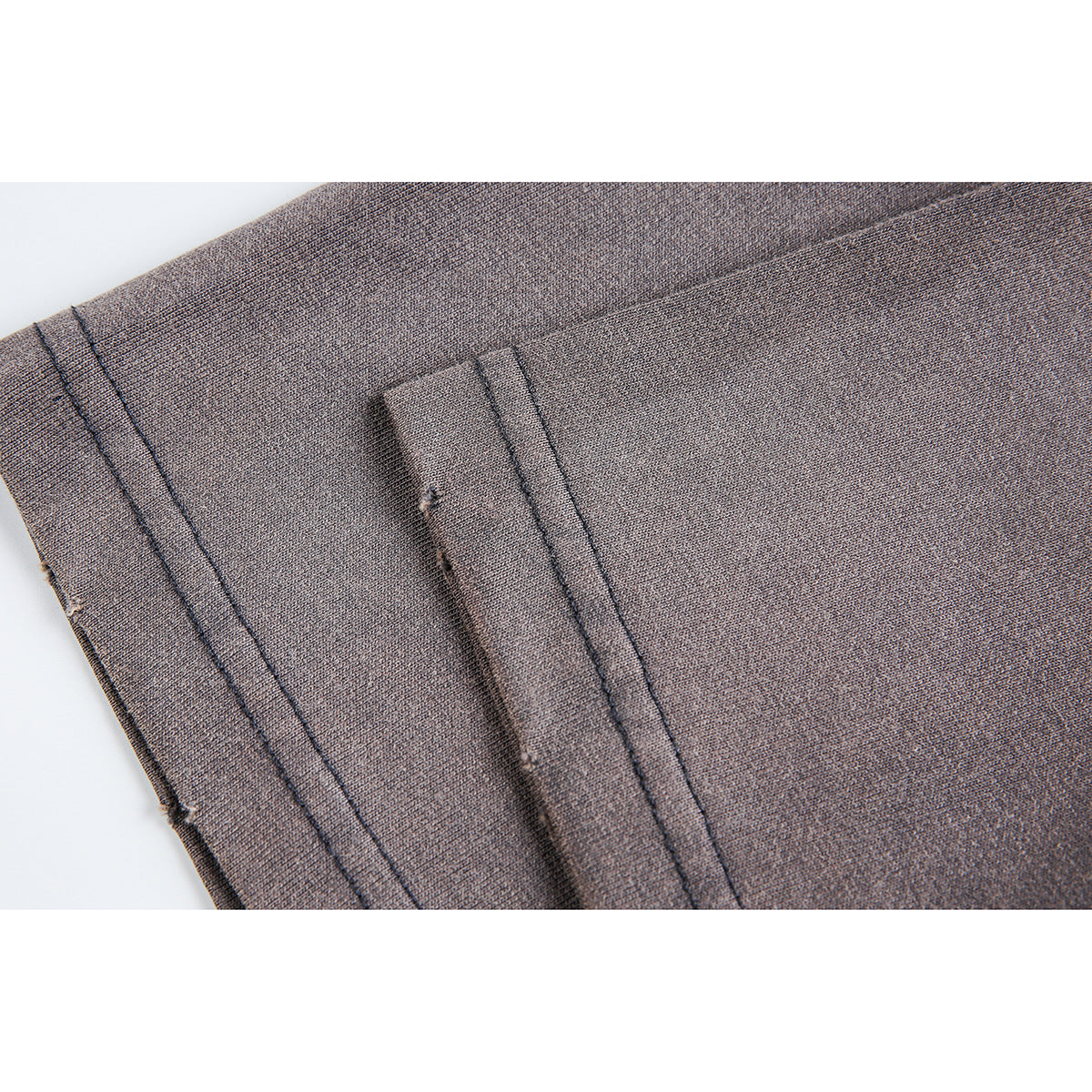 Close-up of gray T-shirt fabric, stitching, and a folded seam.