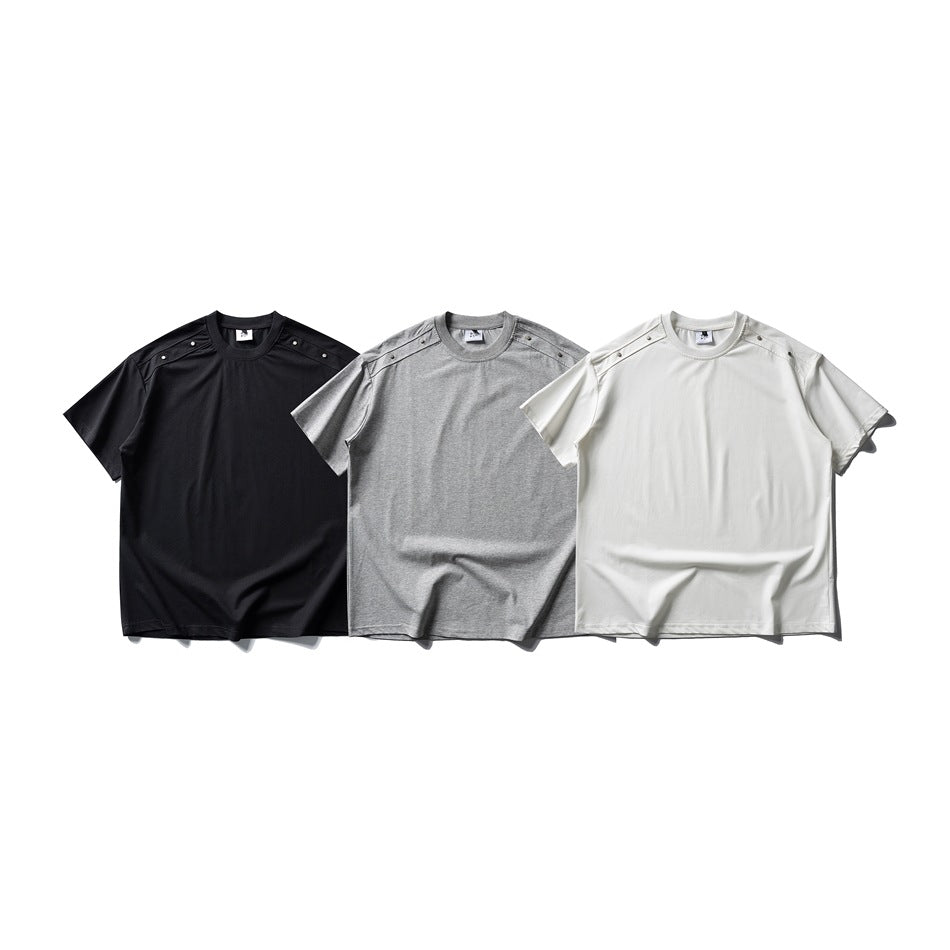 Three short-sleeve crew-neck T-shirts in black, gray and white, shown from the front with buttoned shoulder tabs.