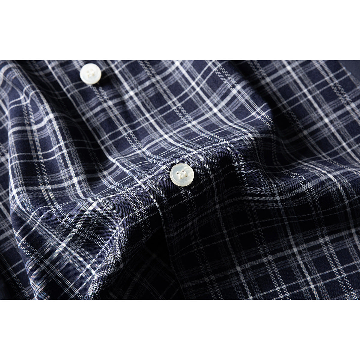 Close-up of navy-and-white plaid shirt fabric with two light-colored buttons.