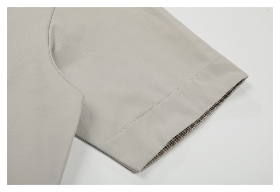 Close-up of a light beige sleeve cuff with a narrow dark checked lining visible at the edge.