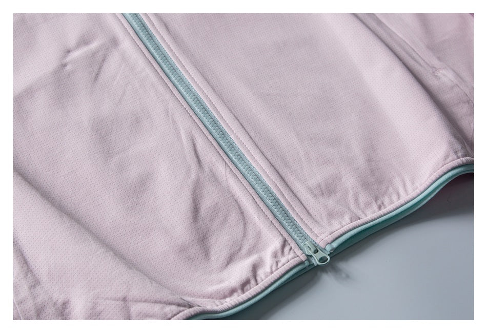Close-up of the pale pink jacket’s mint front zipper and matching trim along the hem.