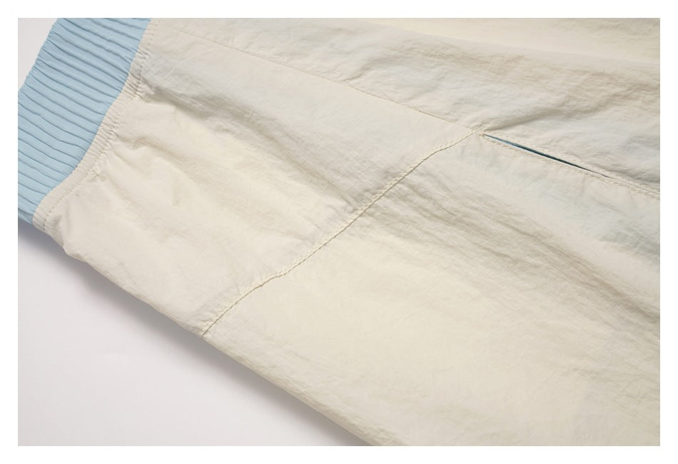 Close-up of the cream skirt’s side seam and pocket opening beside the ribbed light-blue waistband.