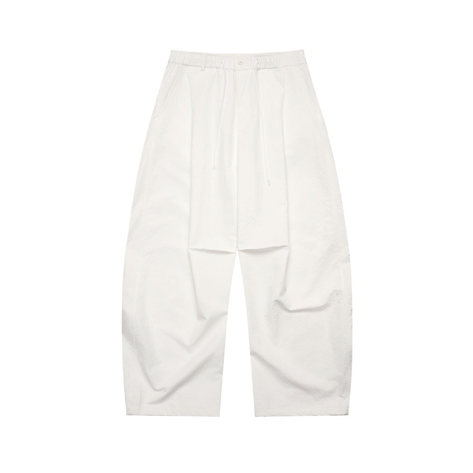 White wide-leg pleated pants with elastic drawstring waist and button front, flat lay
