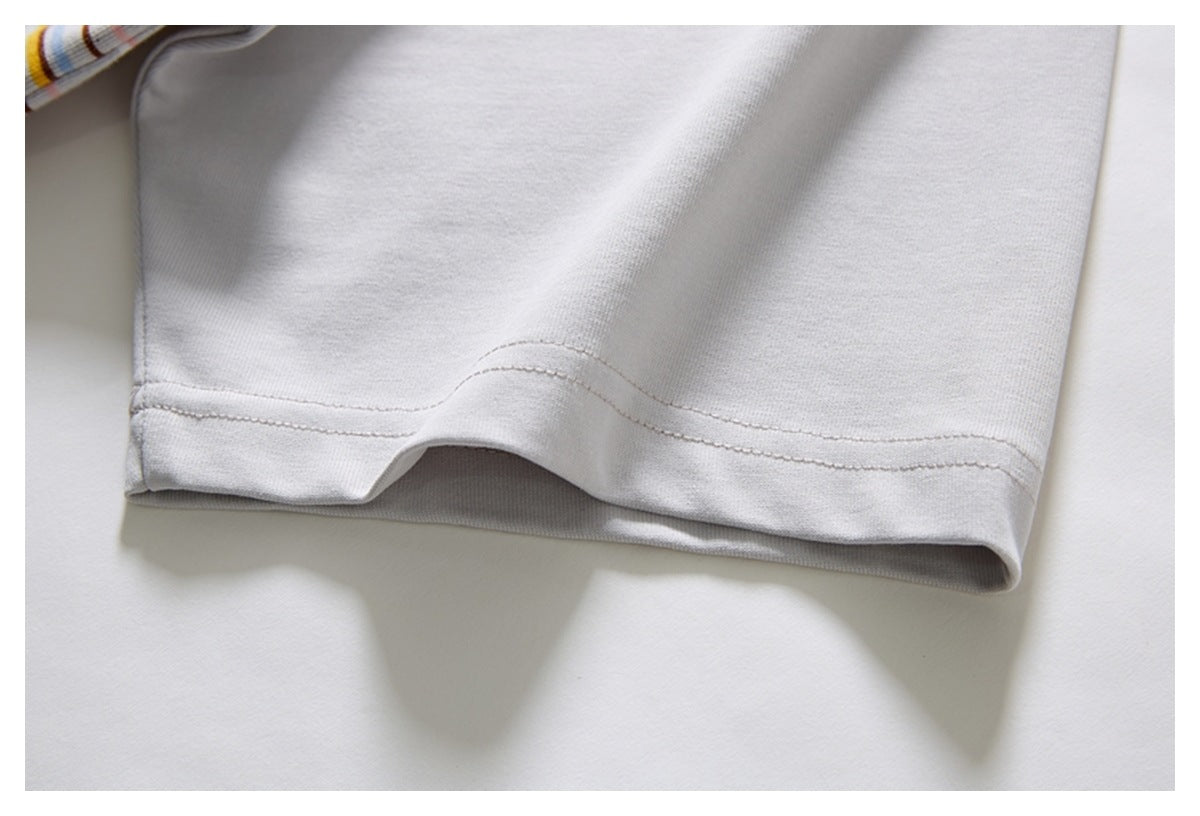 Close-up of a light gray garment hem with visible stitching and a small glimpse of striped fabric.