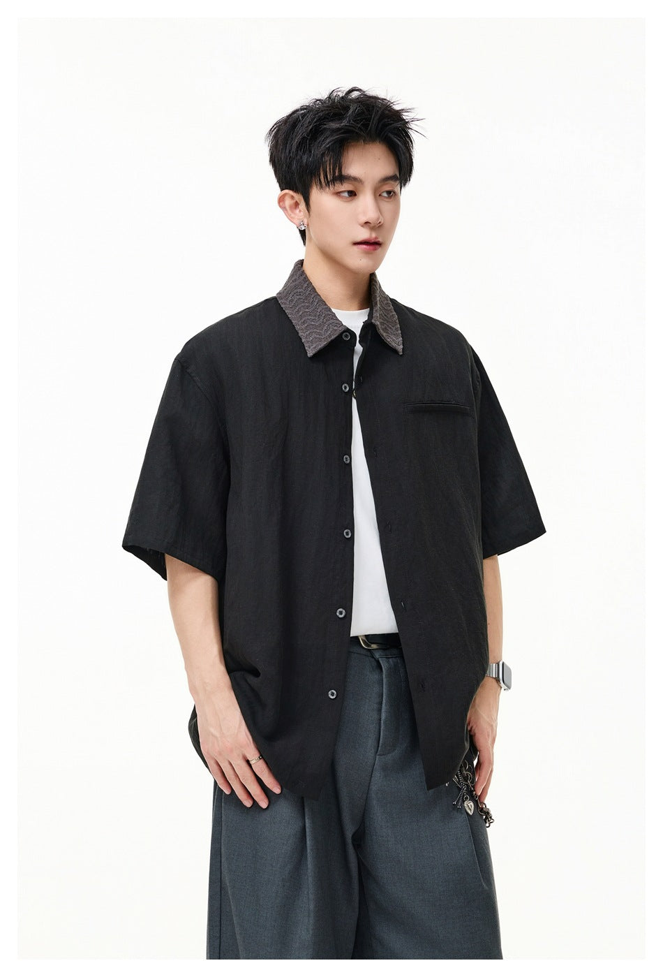 Model wearing open black short-sleeve shirt with gray textured collar over a white tee and gray trousers
