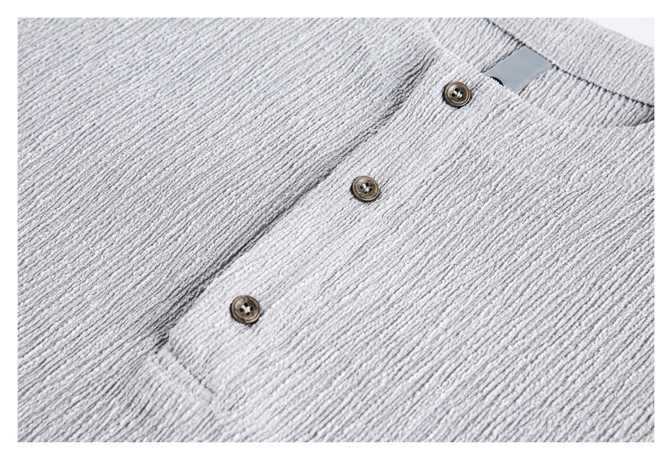 Close-up of a light gray textured top's front placket with three brown buttons.