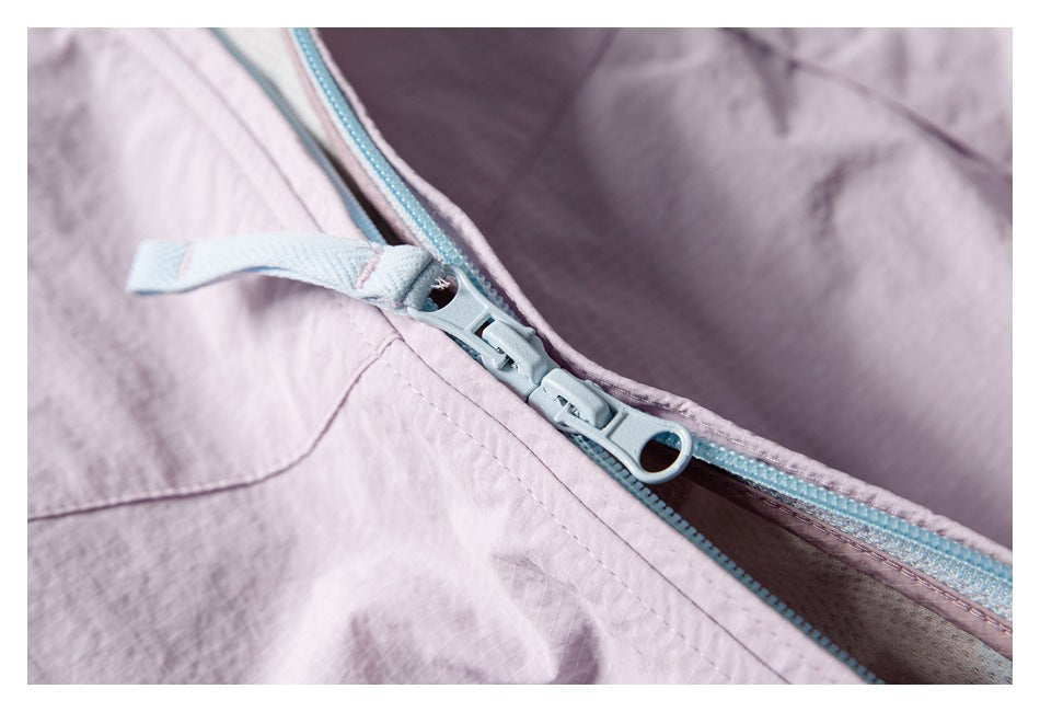 Close-up of two light blue zipper pulls on a pale lavender jacket.