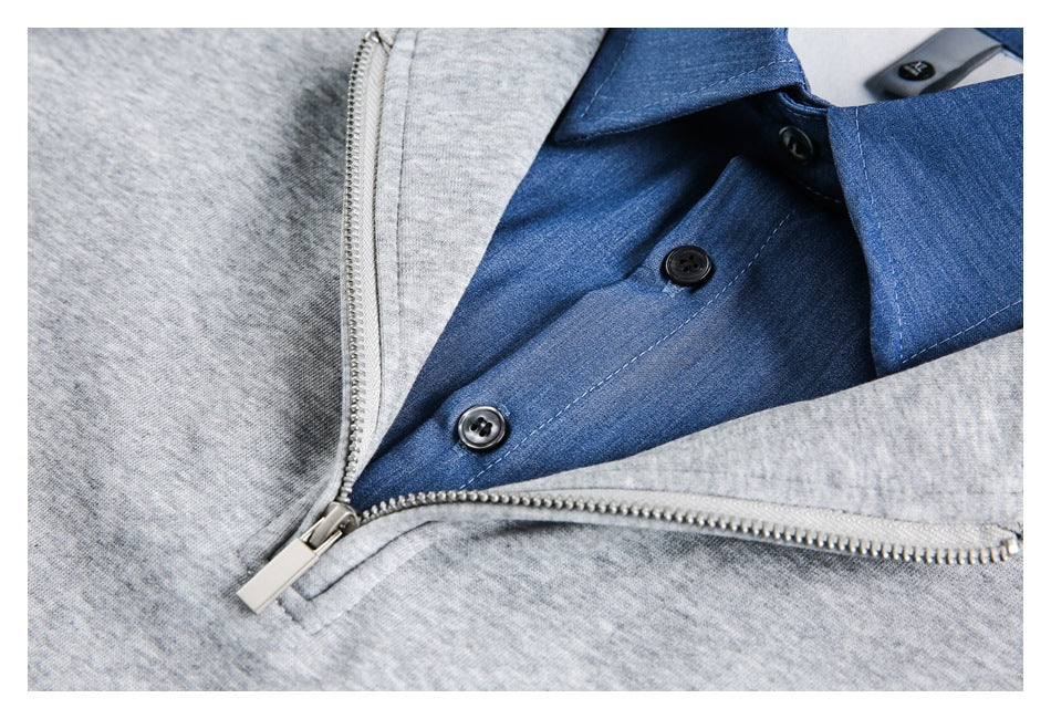 Close-up of a blue button-front shirt beneath the open silver zipper of a gray jacket.
