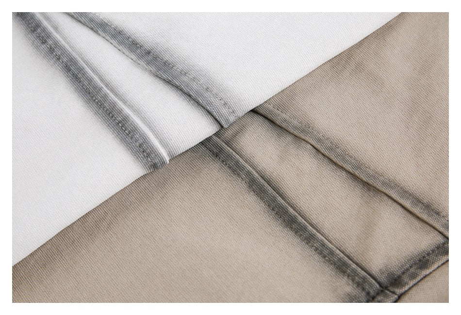 Close-up of white and beige shirt fabric with dark contrast stitching along the seams.