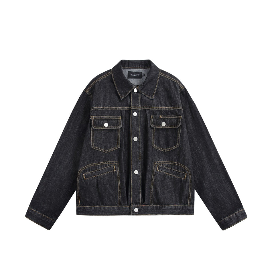 Black washed denim trucker jacket front view with chest flap pockets, curved lower pockets and gold topstitching