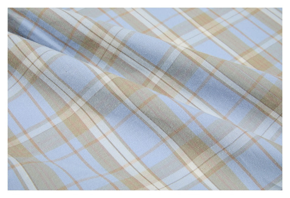 Close-up of the light blue, beige, and white plaid fabric with intersecting stripes.