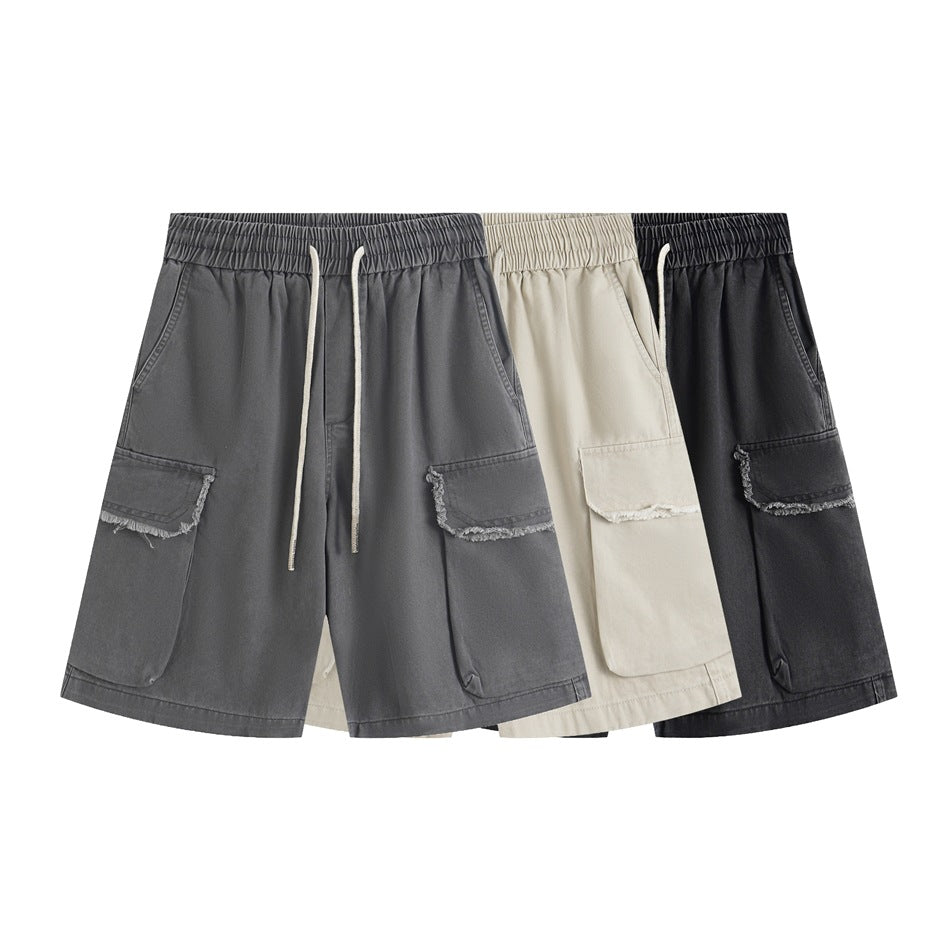Front view of cargo shorts in gray, beige, and black, with elastic waistbands, drawstrings, and frayed pocket flaps.