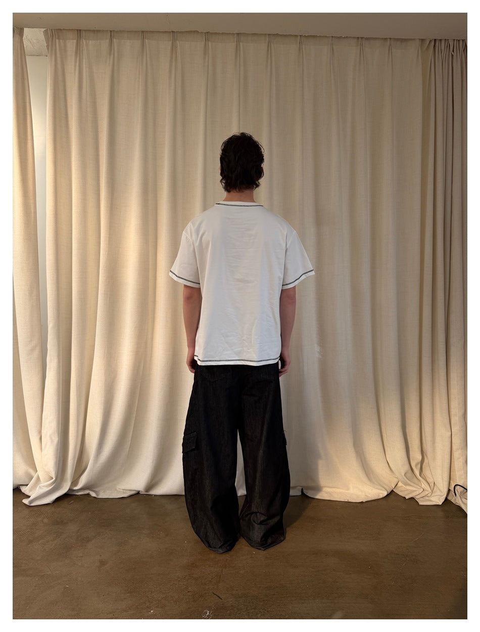 Back view of model wearing the white t-shirt with contrast stitching at neck, sleeves and hem