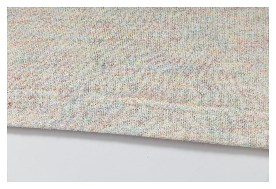 Close-up of the T-shirt’s pastel-speckled knit fabric and stitched bottom hem.