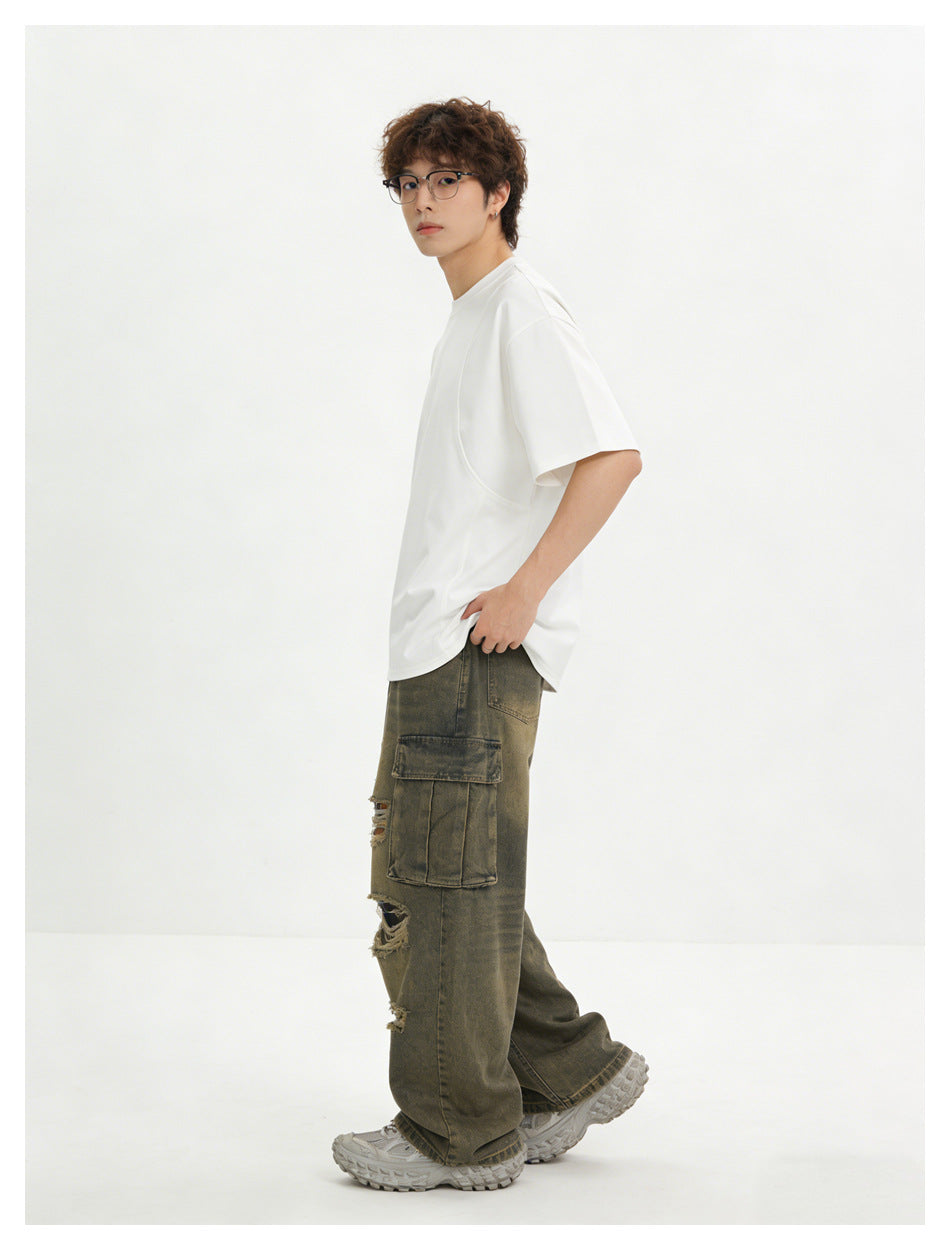 Side view of a model wearing an oversized white T-shirt and distressed olive-gray cargo pants.