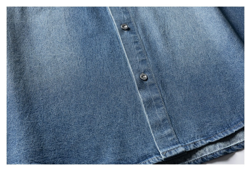 Close-up of a blue denim shirt's button placket with two dark buttons and visible stitching.