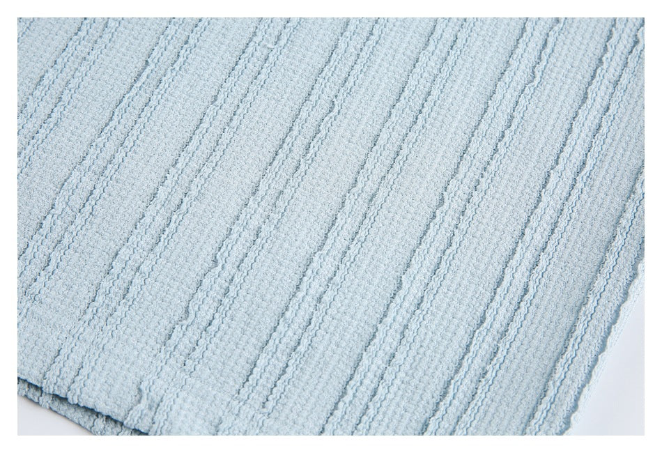 Close-up of pale blue raised vertical fabric texture and a garment edge.