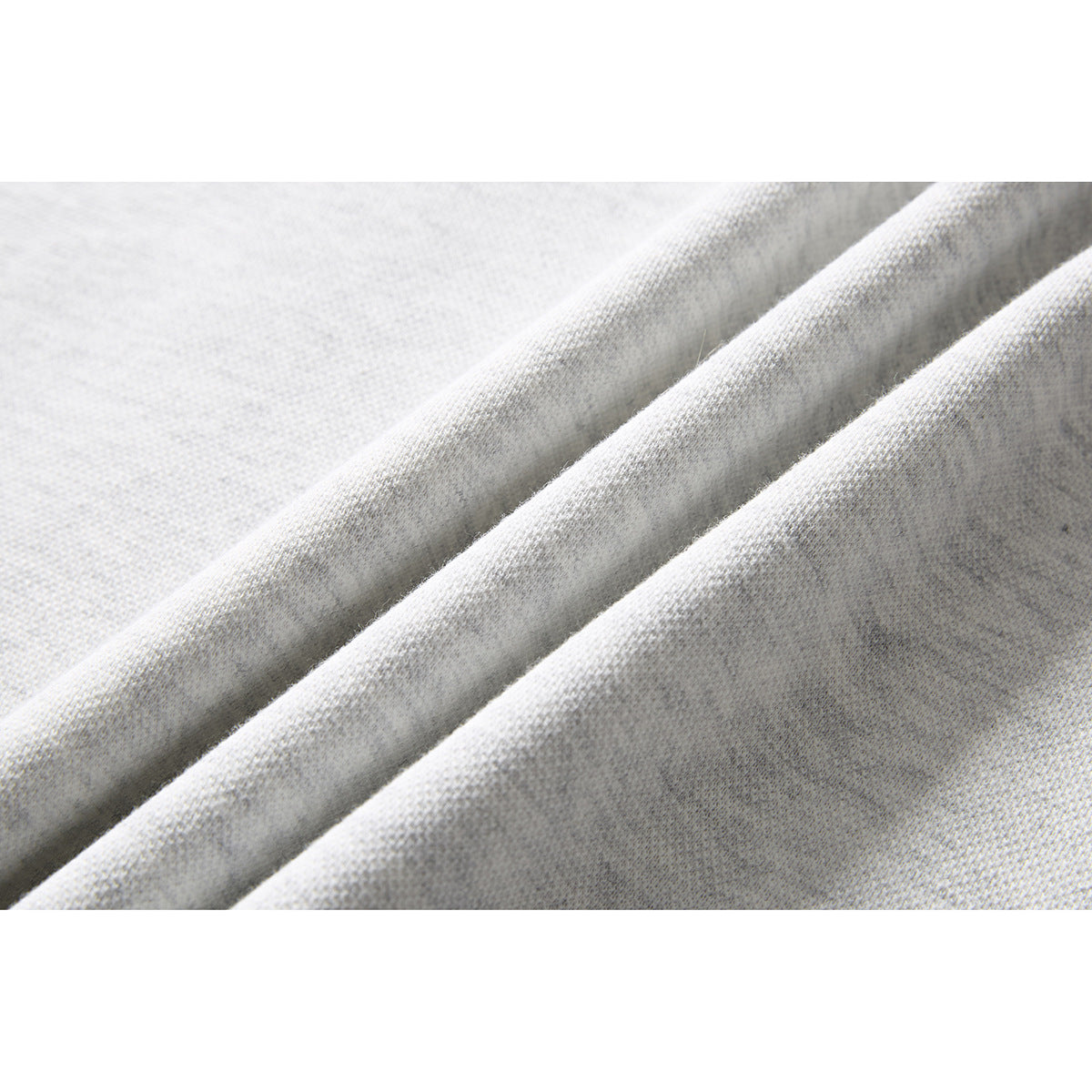 Macro view of light gray knit fabric gathered into soft folds.