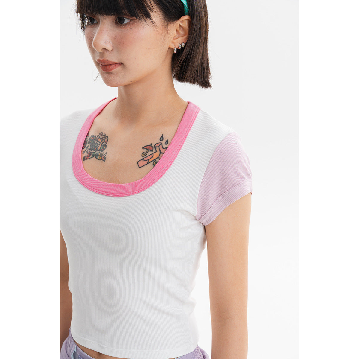 Close-up of a white ribbed cropped top with a bright pink scoop-neck trim and pale pink sleeves.