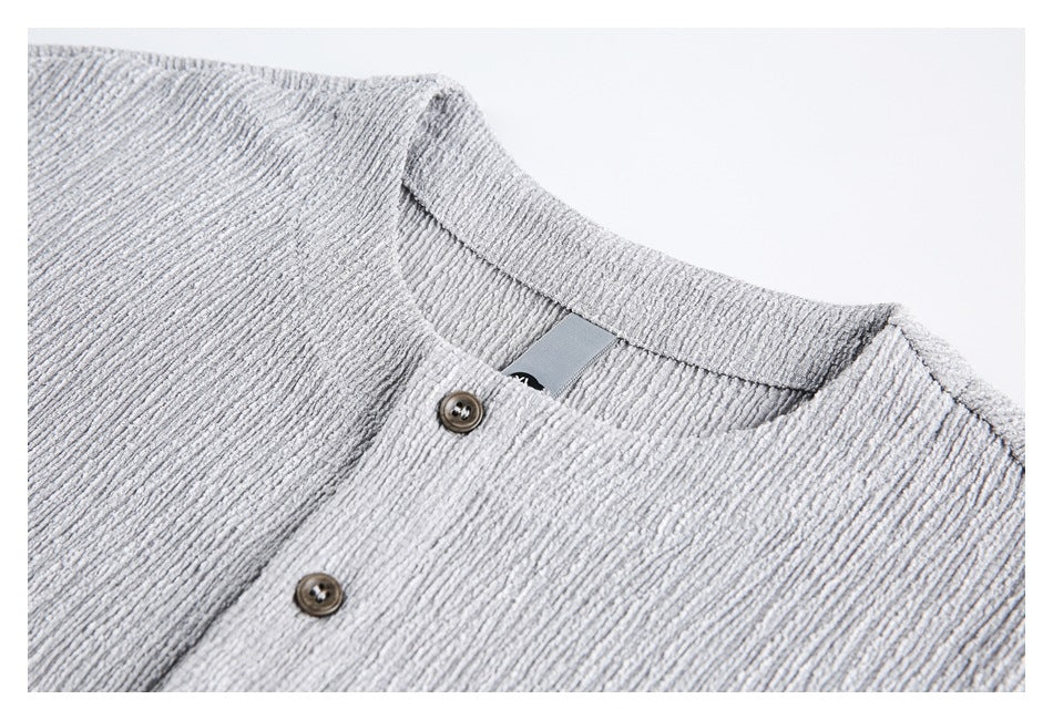 Close-up of a light gray textured top's round neckline and upper button placket.