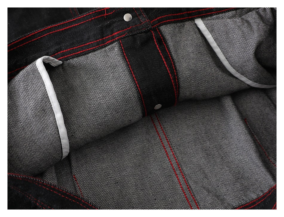 Inside view of the black denim jacket, showing gray reverse fabric, red seam stitching, and white binding.