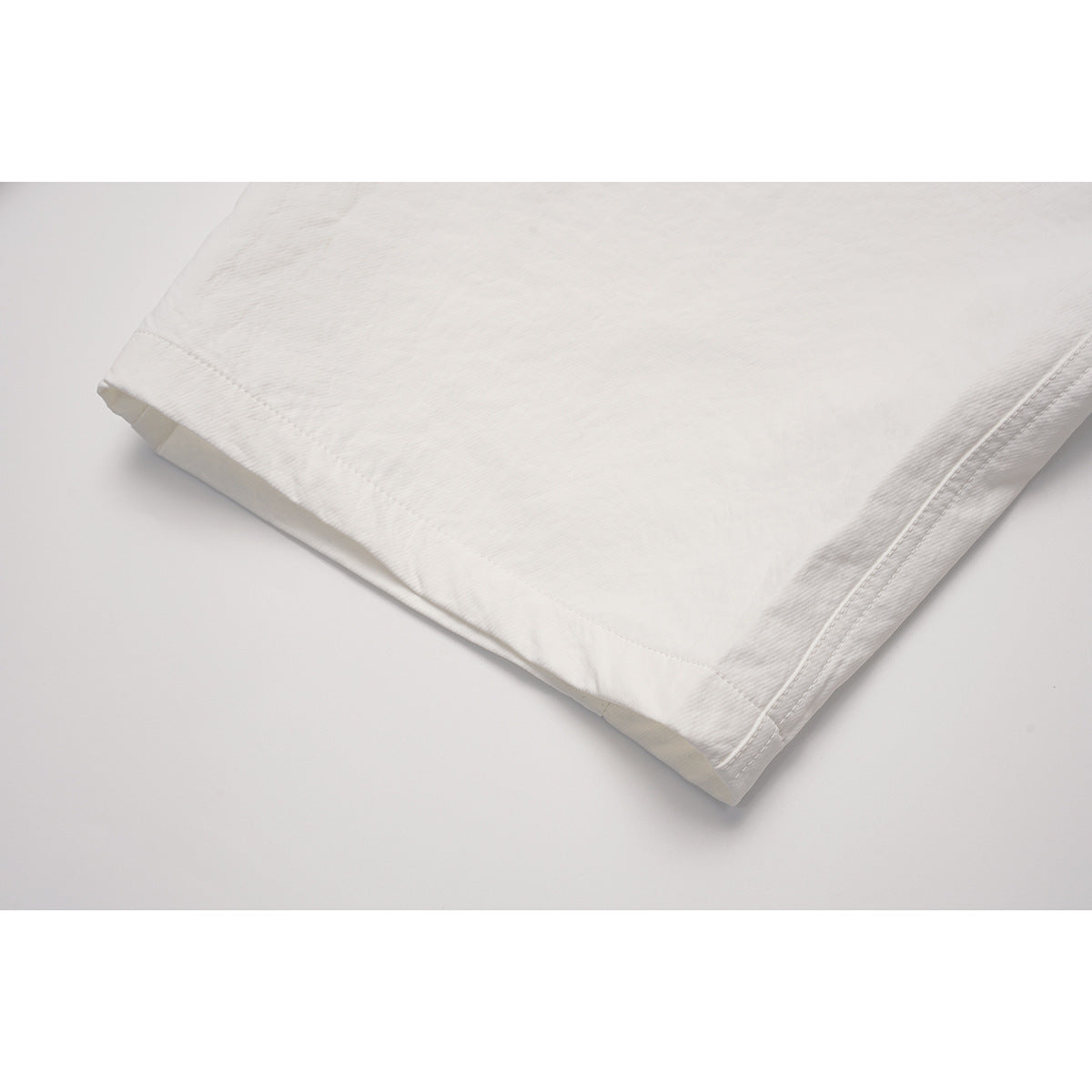 Close-up of the white pants' wide leg and stitched hem.