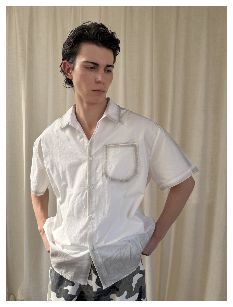 Model wearing a white short-sleeve button-up shirt with a single chest pocket, shown from the front.