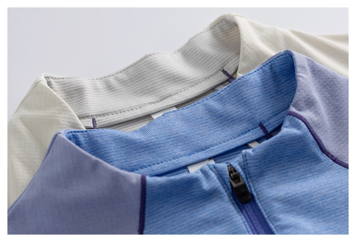Close-up of cream and blue garments showing their collars, purple panels, piping, and front zipper.