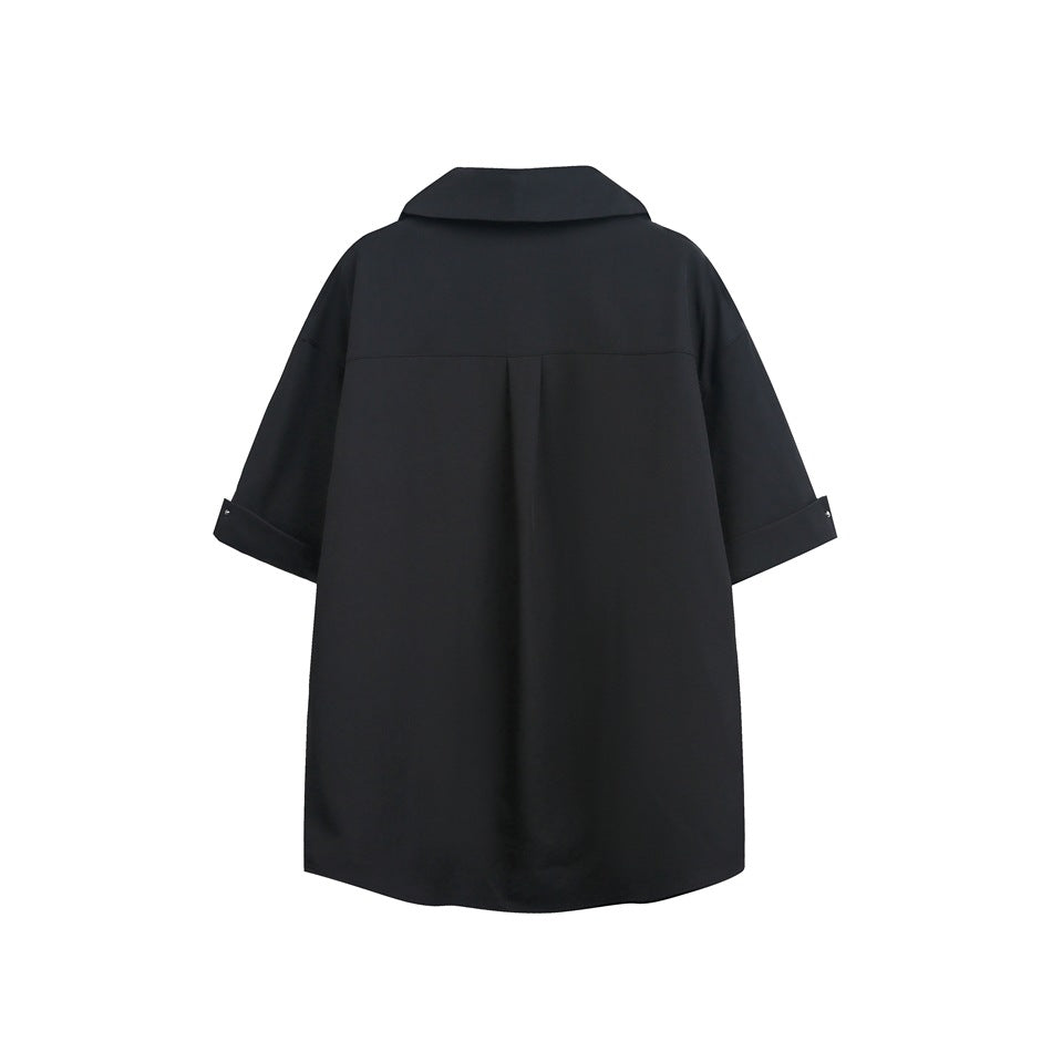 Back view of a loose black collared tunic with short cuffed sleeves and a center back pleat.